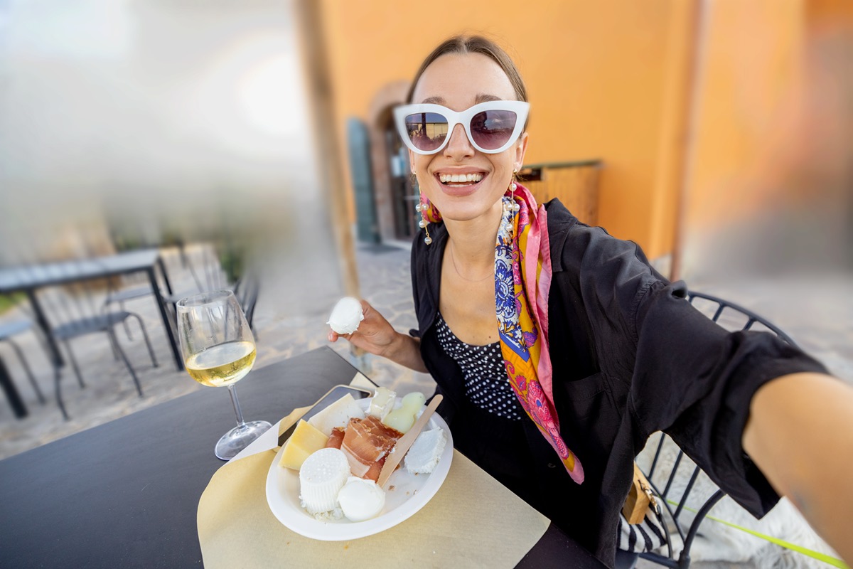 Woman enjoying wine tasting with cheese outdoors